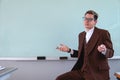 Teacher sitting in front of the class with a confused expression. Professor dressed in a brown suit, a shirt and glasses Royalty Free Stock Photo