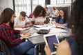 Teacher sitting with high school students using tablets