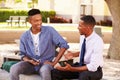 Teacher Sitting Outdoors Helping Male Student With Work