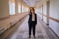 Teacher is standing in empty school corridor. Female school teacher shows pointer while looking at you, concept of isolation due