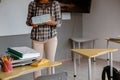 Teacher standing near the school desk with books in hand Royalty Free Stock Photo