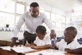 Teacher stands helping elementary school kids at their desks