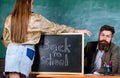 Teacher strict sit table chalkboard background. Student in mini skirt with nice buttocks stand near blackboard. School