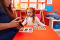Teacher and student playing with maths puzzle game looking cards at kindergarten Royalty Free Stock Photo