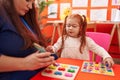 Teacher and student playing with maths puzzle game looking cards at kindergarten Royalty Free Stock Photo