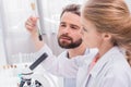 Teacher and student scientists examining green plant with soil in test tube Royalty Free Stock Photo