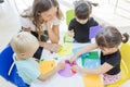 Teacher and students gluing trinkets on a paper