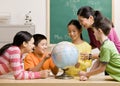 Teacher and students viewing globe in classroom Royalty Free Stock Photo