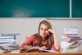 Teacher surrounded by books sitting in school classroom. Royalty Free Stock Photo