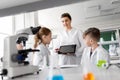 Teacher with tablet pc and kids at chemistry class