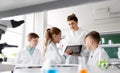 Teacher with tablet pc and kids at chemistry class