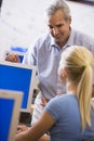 A teacher talks to a schoolgirl using a computer