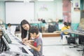 Teacher teach keyboard electone instument to a boy in the class room