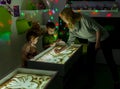 The teacher teaches a girl to draw her fingers on the sand with a back-lit