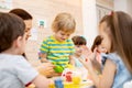 Teacher teaches kids modeling clay in playroom at kindergarten