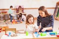 The teacher is teaching the girl to Make sand shapes