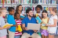 Teacher teaching kids on laptop in library