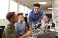 Teacher With Two Male University Students Building Machine In Science Robotics Or Engineering Class