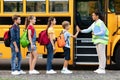 Teacher in uniform giving high five to kids entering school bus Royalty Free Stock Photo