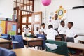 Teacher welcomes kids arriving to elementary school class Royalty Free Stock Photo