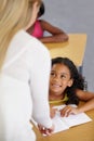 Teacher woman, classroom and help girl at desk with notebook, advice and knowledge for education. People, learning and Royalty Free Stock Photo