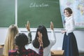 Teacher woman happy and young students who raised their hands is