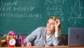 Teacher woman sit table classroom chalkboard background. Teacher busy with paperwork. Work far beyond actual school day