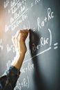 The teacher writes on a board with chalk a formula for electric current.