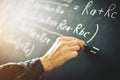 The teacher writes on a board with chalk a formula for electric current.