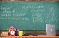 Teachers attributes. Table with school supplies alarm clock books and mug classroom chalkboard background. Working