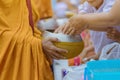 Teachers and students together make merit to give food offerings to a Buddhist monk on important religious days