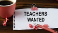 TEACHERS WANTED - words on a white sheet on a wooden brown background with a cup of coffee and a pen Royalty Free Stock Photo