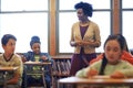 Teaching her favorite subject. a group of elementary children writing a test while a teacher observes.