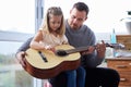 Teaching her some chords. a young father teaching his daughter to play the guitar at home. Royalty Free Stock Photo