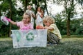 Teaching kids about recycling. Small girl and boy collecting plastic waste in forest with parents, throwing used plastic