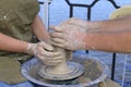 Teaching of wheel throwing. Potter hand correcting woman ones during shaping clay blank on the potters wheel