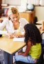 Teaching, writing and teacher helping child at school with education, learning or development. Woman talking to girl Royalty Free Stock Photo