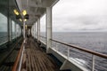 Teak lined Promenade Deck of modern cruise ship on a grey stormy day Royalty Free Stock Photo