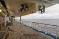 Teak lined Promenade Deck of modern cruise ship on a grey stormy day