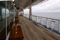 Teak lined Promenade Deck of modern cruise ship on a grey stormy day Royalty Free Stock Photo
