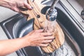 Teak wooden cutting board washing. Woman hands washing teak cutting board.