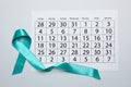 Teal awareness ribbon and calendar on white background, top view. Symbol of social and medical