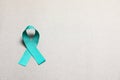 Teal awareness ribbon on grey paper, above view with space for text. Symbol of social and medical