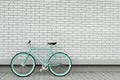 Teal bicycle next to white brick wall