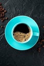 Teal coffee cup and coffee beans, top shot on a black background Royalty Free Stock Photo
