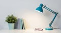 Teal Desk Lamp Illuminating A Stack Of Books And Eyeglasses On A White Surface blue green Royalty Free Stock Photo