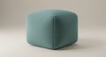 A teal-colored, fabric-covered cube ottoman sits on a neutral background. The ottoma Royalty Free Stock Photo