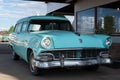 Teal-colored ford ranch wagon parked in front of a store storefront.