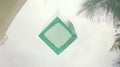 Teal glass cube floats, tropical backdrop, outdoor lighting Royalty Free Stock Photo
