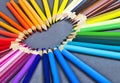 Brightly wooden colored pencils laying on a gray background in the shape of a heart Royalty Free Stock Photo